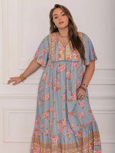  Plus size tie neck maxi dress in a colorful print with flowing flutter sleeves.